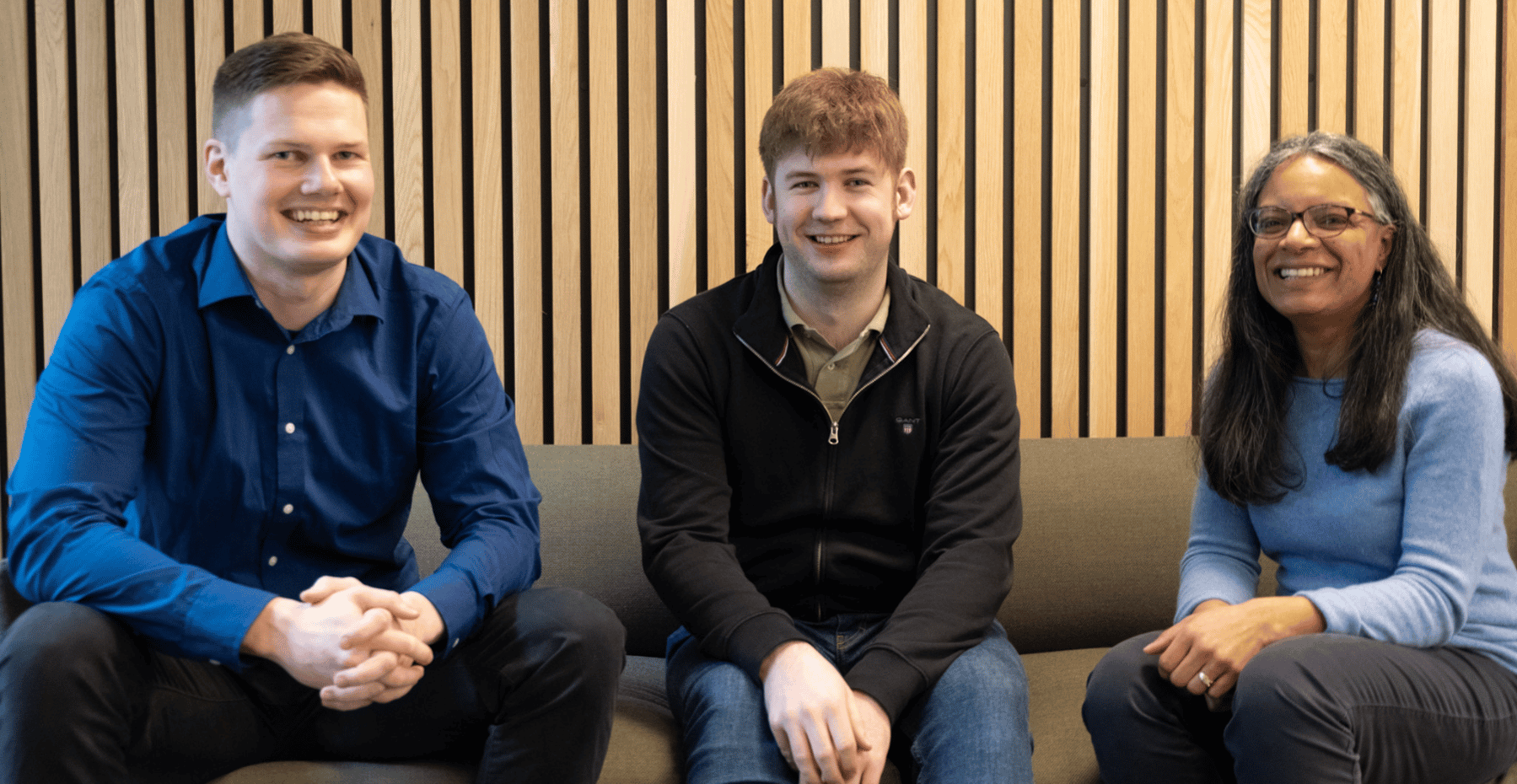 three smiling IT consultants sitting on sofa